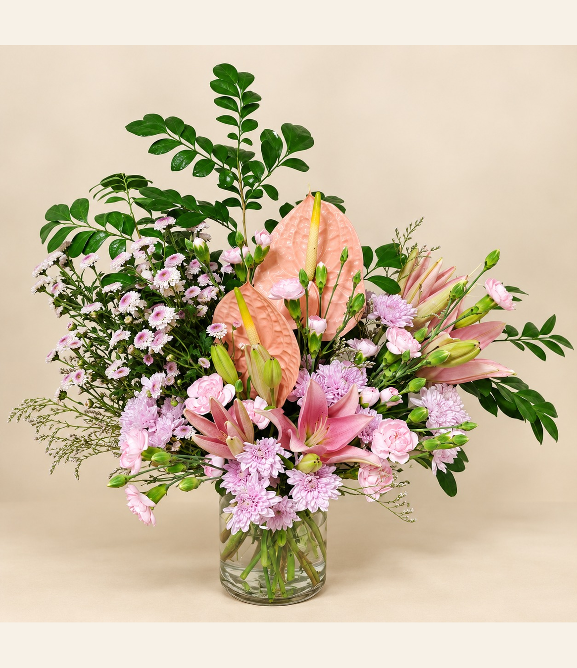 Pink lily and peach anthurium floral arrangement with pink chrysanthemums and fresh greenery by Whitefields.