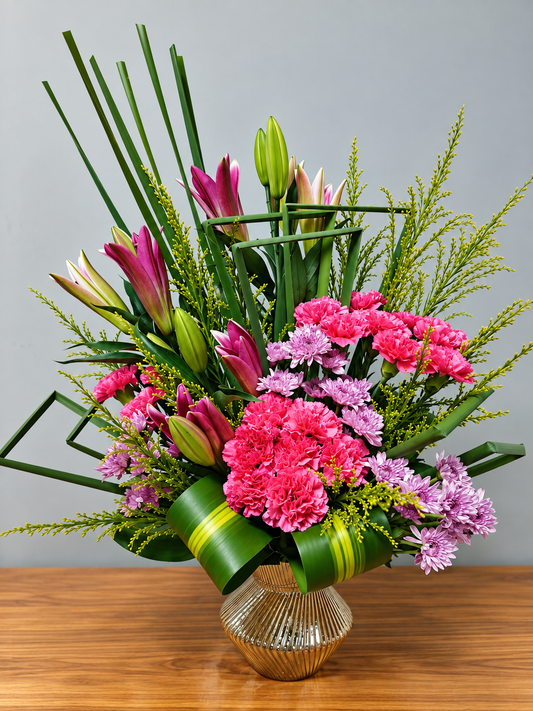 Pink lily and carnation flower arrangement with lavender blooms and lush green foliage by WhiteFields