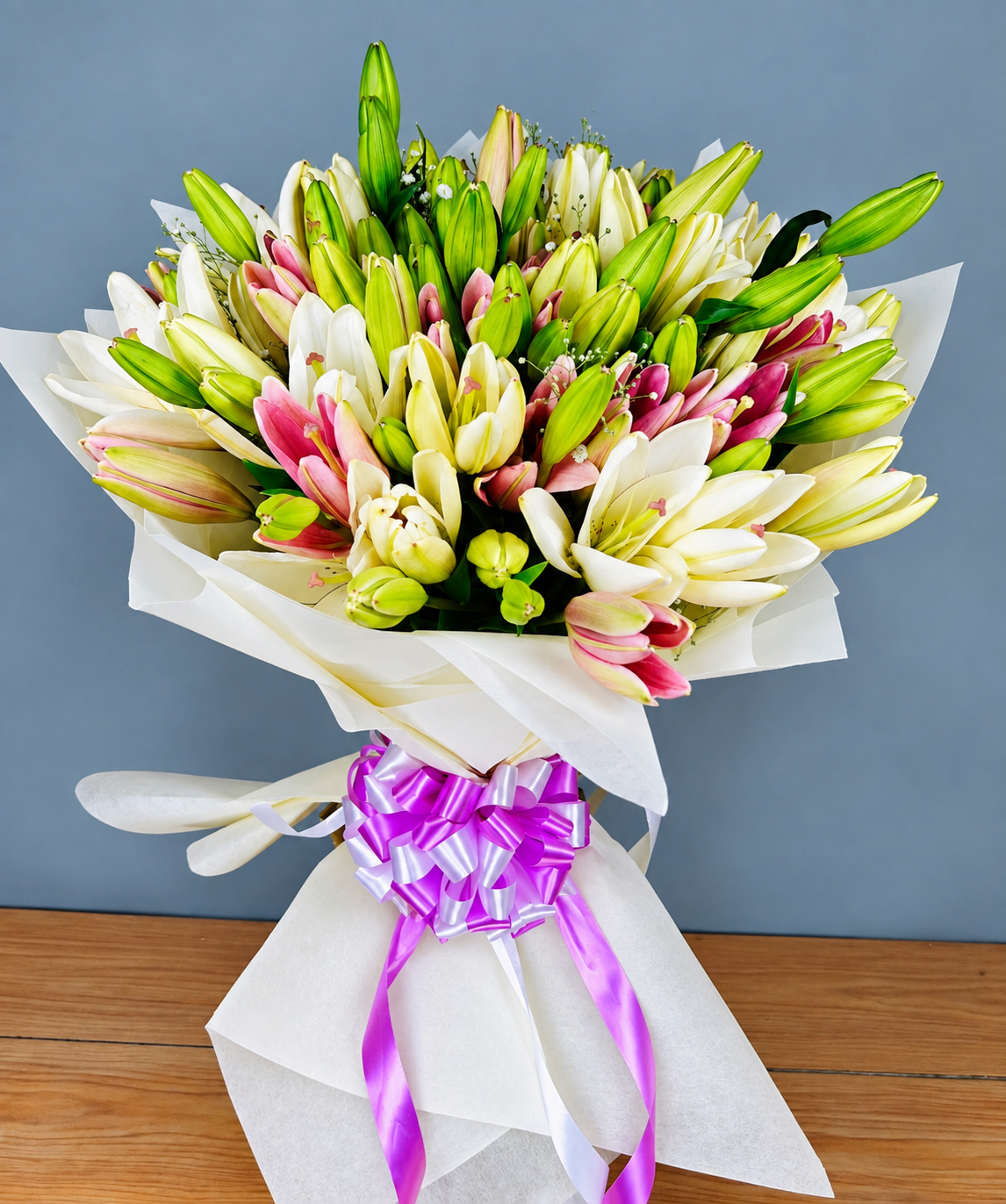 White lily bouquet with pink lily accents, green foliage and white wrapping by WhiteFields